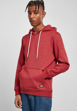 Sweatshirt à capuche rouge avec cordons blancs, poche kangourou, poignets côtelés et une petite étiquette de logo noir à l'ourlet. Tissu texturé.