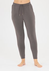Graue, enganliegende Leggings mit weicher Textur. Verfügt über einen elastischen Bund, ein Kordelzugdetail und eine Knöchellänge.