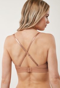 Brązowy biustonosz z regulowanymi, krzyżowanymi na plecach ramiączkami, o gładkiej fakturze i zapięciem na haftki z tyłu dla pewnego dopasowania.