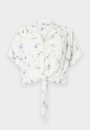 Blusa blanca de manga corta con estampado floral azul, cierre de botones al frente, cuello, ajuste holgado y detalle de lazo delantero en la cintura.