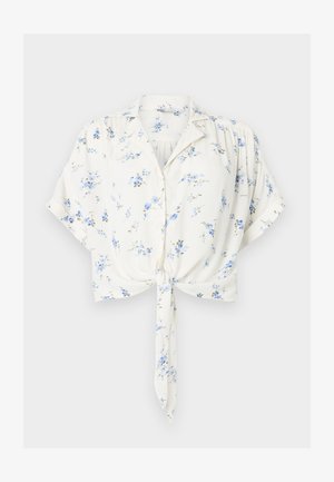 Blusa blanca de manga corta con estampado floral azul, cierre de botones al frente, cuello, ajuste holgado y detalle de lazo delantero en la cintura.