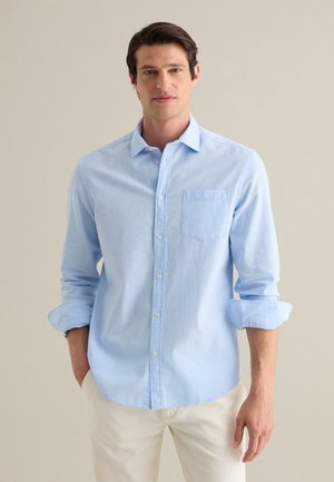 Helle blaue Button-Up-Hemd aus weichem Stoff; hat eine einzelne Brusttasche, lange Ärmel und einen klassischen Kragen.