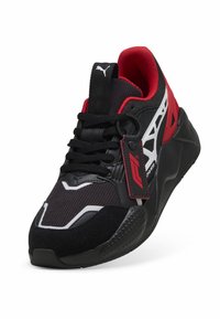 Baskets noires avec accents rouges, tissu texturé, design épuré, détails blancs sur les côtés et col rembourré. Lacets noirs.