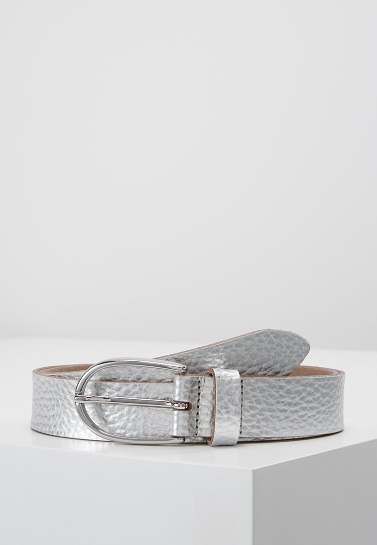 Ceinture en cuir texturé argent avec une boucle métallique argentée arrondie, présentée enroulée sur une surface blanche sur fond gris uni.