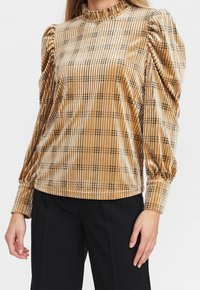 Top in velluto oro con collo alto arricciato, maniche a sbuffo e motivo a scacchi neri, con orlo elasticizzato.