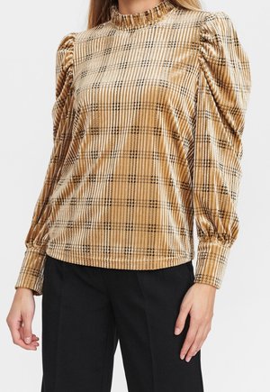 Top en velours doré avec un col haut à volants, des manches bouffantes et un motif à carreaux noirs, avec un ourlet élastiqué.