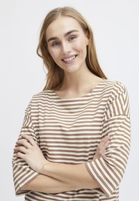 Top a righe con strisce orizzontali marroni e crema, scollatura tonda e maniche morbide. Il materiale sembra morbido e liscio.