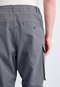 Gray cargo pants made of lightweight material, featuring an elastic waistband, back pockets, and a side pocket for added functionality.