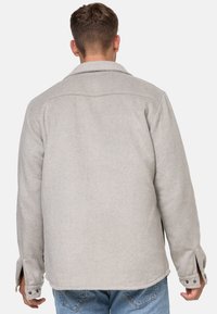 Giacca in misto lana grigia con colletto a punta, polsini con bottoni e vestibilità morbida. Vista posteriore che mostra il tessuto strutturato e le cuciture pulite.