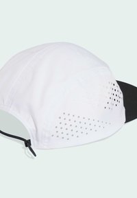 Cappello sportivo bianco con visiera nera, dotato di perforazioni sui lati per la traspirabilità e chiusura a coulisse per una vestibilità regolabile.