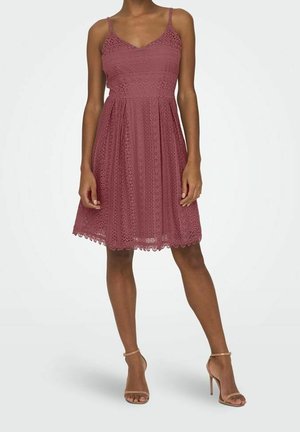 Lace dress in dusty rose with a fitted bodice and flared skirt. Features thin straps and scalloped hem detailing.
