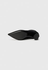 Svart høye heler med spiss tå, laget av semsket skinn. Har et elegant design og en glatt såle. Høyden på hælen er moderat.