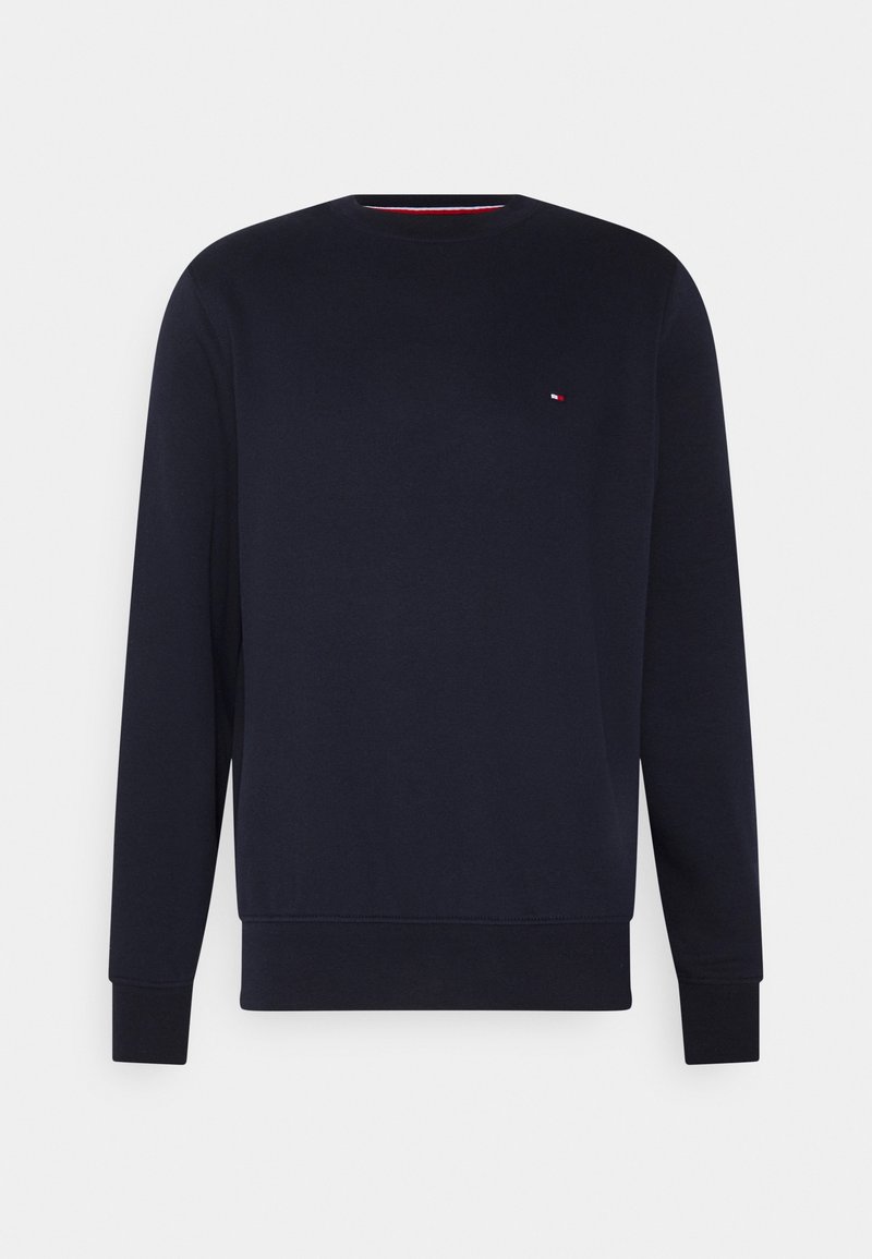 Sweat-shirt bleu marine à col rond avec manches longues, poignets et ourlet côtelés, arborant un petit logo rouge, blanc et bleu sur la poitrine gauche.