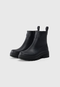 Bottines noires avec semelles épaisses, languettes de tirage marquées et logo en relief sur la partie supérieure avant.
