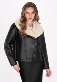 Schwarze Lederjacke mit einem breiten Kragen aus cremefarbenem Kunstfell, Reißverschluss und seitlichen Taschen. Glatte Textur und kurzes Design.