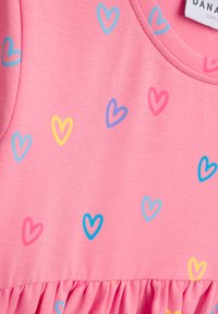 Rosa Baumwollkleid mit gerafftem Saum, verziert mit kleinen Herzmustern in Blau, Pink, Gelb und Lila.