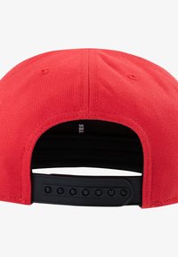Rød baseballkasket med tekstureret stof. Har en sort justerbar snapback-lukning og synlige syninger langs sømmene.