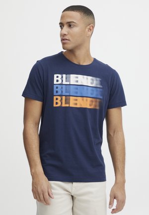 Navy blue cotton t-shirt featuring a graphic design with the word "BLEND" in varying colors of white, blue, and orange. Short sleeves, crew neckline.