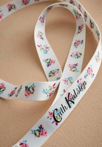 Lilleline puuvillane pael, millel on valge taust ning roosa, sinine ja roheline lill. Sisaldab musta "Cath Kidston" brändinime.
