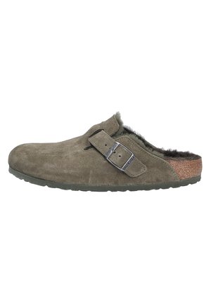 Mule de ante gris-verde con forro de pelo, correa ajustable y media suela de corcho. Cuenta con una suela de goma texturizada para agarre y durabilidad.