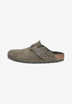 Mule de ante gris-verde con forro de pelo, correa ajustable y media suela de corcho. Cuenta con una suela de goma texturizada para agarre y durabilidad.