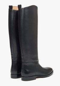 Czarne skórzane kozaki za kolano o gładkiej teksturze, zaokrąglonym nosku i niskim, szerokim obcasie, wyposażone w materiałowe pętelki na górze ułatwiające zakładanie.