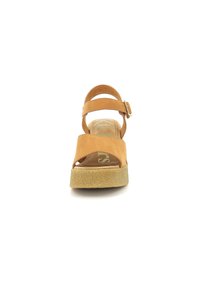 Sandal de ante marrón con punta abierta, correa ajustable en el tobillo y suela de corcho para aumentar la altura. Textura suave y diseño simple.
