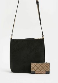 Borsa a tracolla nera con cintura regolabile e zip in oro, abbinata a un piccolo portafoglio con zip marrone a fantasia.