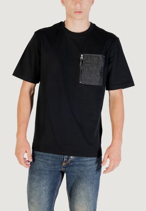 T-shirt nera a maniche corte con taschino in denim grigio dotato di zip. Tessuto morbido, vestibilità rilassata e collo a giro.