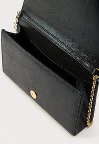 Μαύρο τσάκι χειρός από υλικό με υφή, με χρυσό κούμπωμα και αλυσίδα για τον ώμο. Ανοιχτός εσωτερικός σχεδιασμός.