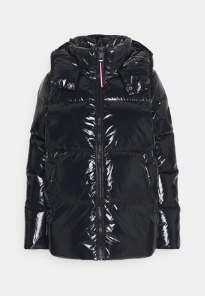 Veste d’hiver matelassée noire brillante avec col montant, fermeture éclair à l’avant, deux poches latérales et capuche amovible avec boutons-pression.