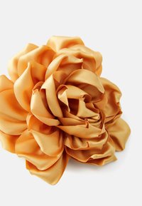 Accessorio in tessuto satinato di colore arancione dorato caldo, con petali sovrapposti dal texture liscia e un design naturalistico.