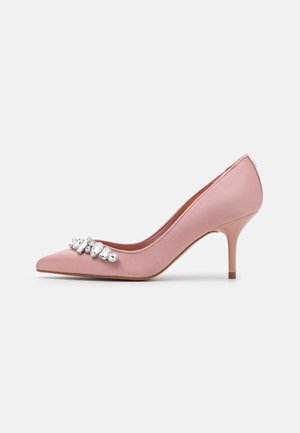 Roze satijnen pumps met een scherpe neus en decoratieve transparante strasstenen aan de voorkant, zijaanzicht op een witte achtergrond.