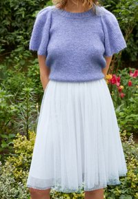 Lichtpaarse gebreide trui met korte, puffed mouwen, gecombineerd met een witte tule rok met kleine, subtiele stippen.