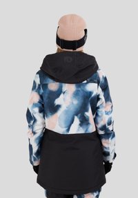 Wielokolorowa kurtka izolacyjna z wzorem akwarelowym w odcieniach niebieskiego, różowego i czarnego. Posiada kaptur i akcenty na ramionach w jednolitym czarnym kolorze.