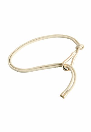 Beige stoffen riem met goudkleurige metalen haaksluiting en goudkleurige metalen uiteinden, dichtgeknoopt vlakbij de sluiting.