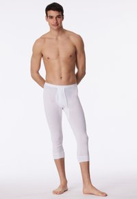 Leggings en coton blanc avec un design ajusté, longueur trois quarts, taille élastique et poignets côtelés au bas de la jambe.