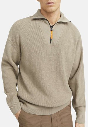 Pull-over en tricot beige avec un col zippé à mi-hauteur. Comprend un tissu texturé, des poignets et un ourlet côtelés, ainsi qu'un détail en forme de V près du col.