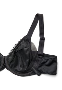 Melna krūšturis ar mežģīņu apdari, izgatavots no acs un satīna materiāliem, ar stiepļiem, regulējamiem siksniņām un aizdares āķi. Krūšu kausiem ir viļņotas malas.