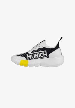 Zapatilla en blanco y negro con parte superior de punto, que presenta un prominente logotipo "MUNICH", acentuado por un talón amarillo y una suela blanca gruesa.