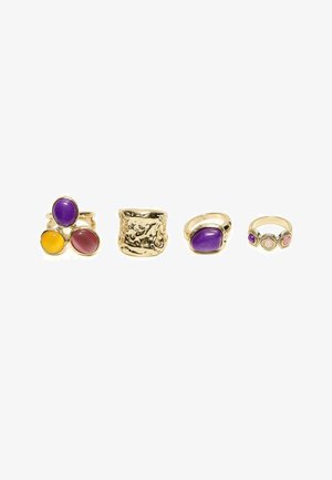 Four gold rings with colored stones: one has three large oval stones in purple, yellow, and pink, one textured gold band, one oval purple stone, one with three small round stones.
