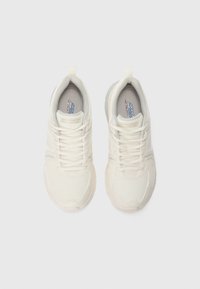 Une paire de baskets Skechers couleur crème avec des lacets et des semelles en mousse à mémoire, vue de dessus sur un fond blanc.