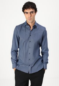 Cămașă albastră în carouri, dintr-un material ușor, cu guler, mâneci lungi și nasturi negri. Pur tată cu pantaloni închisi la culoare.