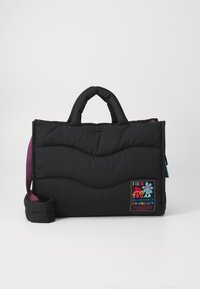 Svart polstret veske med bølget design, doble håndtak og en lilla skulderrem. Har et fargerikt merke med tekst og blomstrende detaljer.