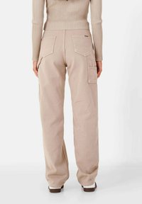 Beige cargobroek met een relaxte pasvorm, voorzien van twee achterzakken en een zijzak. Gemaakt van duurzaam stof met een zachte textuur.