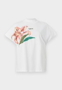 T-shirt bianca in cotone con maniche corte, caratterizzata da un motivo floreale rosa e foglie verdi sul lato sinistro. Logo "Guess" in grigio sopra il motivo.