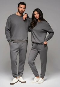Graue passende Sweatshirts und Jogginghosen aus einem weichen Stoff. Die Sweatshirts haben Rundhalsausschnitte; die Hosen verfügen über elastische Bündchen und einen verstellbaren Bund.