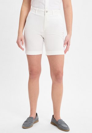 White cotton shorts with a high waist, rolled cuffs, and front pockets. Paired with gray suede loafers. Plain background.