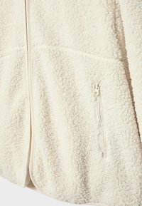 Weiße Fleecejacke mit strukturiertem Oberflächenmaterial, Frontreißverschluss und kleiner seitlicher Reißverschlusstasche. Weiches Material mit lässiger Passform.