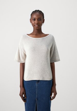 Pull en maille gris clair avec un col large et des manches courtes, présentant un ourlet côtelé. Associé à une jupe en denim bleue.